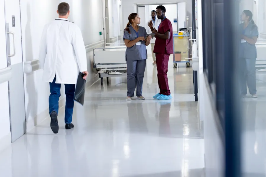 Physicians conferring in a busy hospital corridor